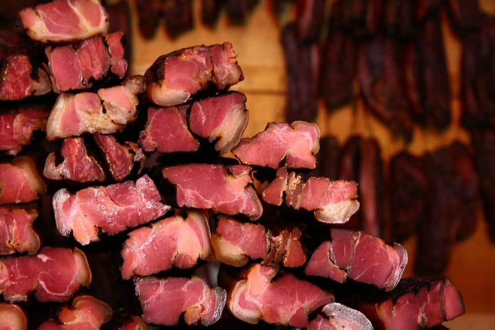 烟熏腊肉切片与背景悬挂肉